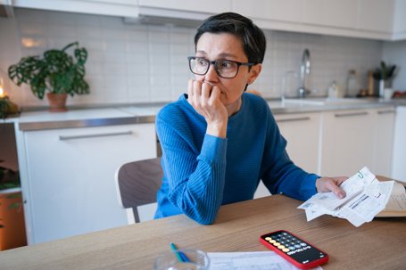 Concerned upset mature woman calculating bills and budget, balancing finances and debts at home