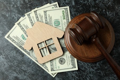 Judge gavel, dollars and wooden house on black smokey table