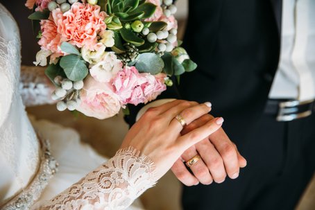 Closeup groom and bride are holding hands at wedding day ang show rings